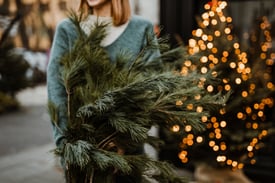 A woman is holding pine branches in her hands