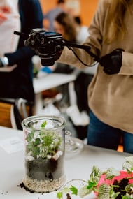 Woman taking a photo of terrarium with plants